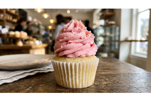 Close-up of a jumbo cupcake with tall pink layered buttercream frosting, used to illustrate decorated height for cupcake container dome height selection.